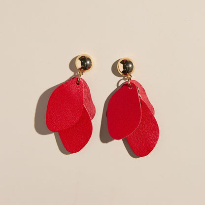 Red earrings with gold accents on a beige background