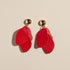 Red earrings with gold accents on a beige background