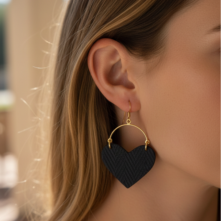 Heart-shaped earrings with gold loops on a beige background