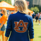 Person wearing a blue jacket with an Auburn logo outdoors
