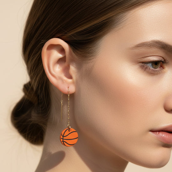 Basketball-themed earrings with chain drops on a beige background