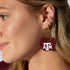 Close-up of a person wearing maroon earrings with &