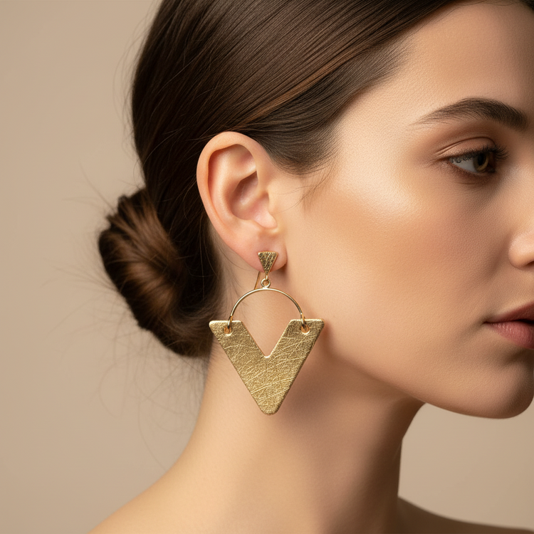 Gold geometric earrings on a beige background