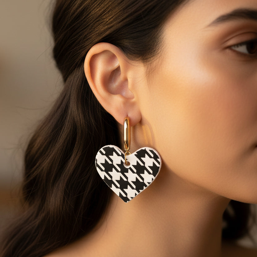 Heart-shaped earrings with black and white houndstooth pattern on a beige background