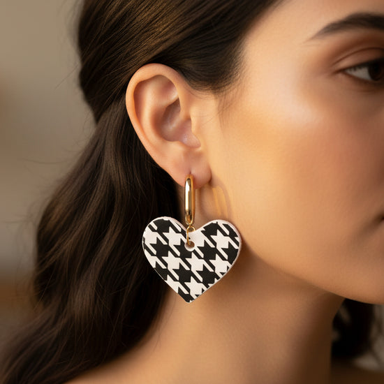 Heart-shaped earrings with black and white houndstooth pattern on a beige background
