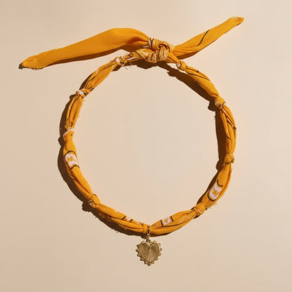 Yellow headband with a decorative pendant on a beige background