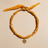 Yellow headband with a decorative pendant on a beige background