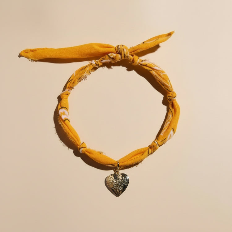 Yellow headband with a heart-shaped pendant on a beige background
